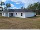 Backyard view of a one-story home featuring a dark roof, white siding, and covered patio at 12929 Sw 82Nd Avenue Rd, Ocala, FL 34473