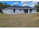 Backyard view of a one-story home featuring a dark roof, gray siding, and covered patio at 12929 Sw 82Nd Avenue Rd, Ocala, FL 34473