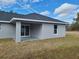 Backyard view of a one-story home featuring a dark roof, gray siding, and covered patio at 12929 Sw 82Nd Avenue Rd, Ocala, FL 34473