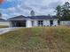 A modern single-story home showcases a white exterior, black roof, and an inviting open garage at 12929 Sw 82Nd Avenue Rd, Ocala, FL 34473