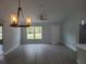 Open-concept living room featuring modern light fixtures, neutral paint, and durable light wood-look flooring at 12929 Sw 82Nd Avenue Rd, Ocala, FL 34473