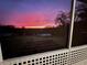 Backyard scene showcases vibrant sunset colors with a view framed through a window with white trim at 13045 Mountain Trail, Clermont, FL 34715