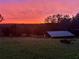 Backyard landscape featuring a shed with a gorgeous sunset, lush green grass, and open space at 13045 Mountain Trail, Clermont, FL 34715