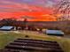 Gorgeous backyard view with a fiery sunset, lush green grass, and two sheds in the distance at 13045 Mountain Trail, Clermont, FL 34715