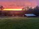 Vibrant sunset over backyard featuring lush green grass and a shed, creating a peaceful scene at 13045 Mountain Trail, Clermont, FL 34715