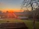 Beautiful sunset view overlooking a backyard with lush green grass, a shed, and garden beds at 13045 Mountain Trail, Clermont, FL 34715