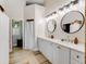 Bright bathroom featuring a double sink vanity with round mirrors and modern lighting at 13045 Mountain Trail, Clermont, FL 34715