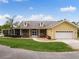 Inviting yellow house with a well-kept lawn, covered front porch, and attached garage at 13045 Mountain Trail, Clermont, FL 34715