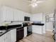 Bright kitchen featuring white cabinetry, black appliances, granite countertops, and wood-look tile flooring at 13045 Mountain Trail, Clermont, FL 34715