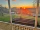 Sunset view from the porch showcasing lush green grass, two sheds, and garden beds at 13045 Mountain Trail, Clermont, FL 34715