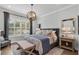 Well-lit bedroom featuring a stylish light fixture, upholstered headboard, comfortable bench, and wood floors at 1324 Utah Blvd, Orlando, FL 32803