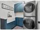 Well-lit laundry room featuring stacked washer and dryer, blue cabinetry, farmhouse sink, and stylish patterned floor at 1324 Utah Blvd, Orlando, FL 32803