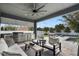 A covered outdoor kitchen with a stainless steel grill, mini fridge, fan, seating area, and a view of the pool and backyard at 1324 Utah Blvd, Orlando, FL 32803