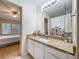 Bright bathroom featuring granite countertops, white cabinets, a large mirror, and a peek into the bedroom at 1410 Stockton Dr, Sanford, FL 32771