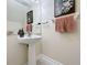 Stylish powder room features pedestal sink, framed artwork, and tile floors at 1410 Stockton Dr, Sanford, FL 32771