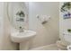 Cozy powder room features a pedestal sink, oval mirror, and neutral decor at 1411 Pacific Rd, Poinciana, FL 34759