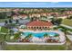 Aerial view of a community clubhouse with a large pool, palm trees, lounge chairs, and manicured landscaping at 1411 Pacific Rd, Poinciana, FL 34759