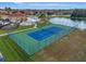 Aerial view of a well-maintained blue and green tennis court next to a pond at 1411 Pacific Rd, Poinciana, FL 34759