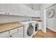 Well-lit laundry room featuring granite countertops, wood floors, and custom white cabinets at 1554 Eagle Nest Cir, Winter Springs, FL 32708