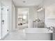 A bright bathroom featuring a soaking tub, a glass-enclosed shower, marble flooring, and an ensuite to the main bedroom at 16420 Silver Grove Blvd, Winter Garden, FL 34787