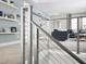 Modern staircase with metal cable railing looking into a cozy living room with a navy sofa and decorative shelving at 16420 Silver Grove Blvd, Winter Garden, FL 34787