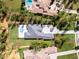 An aerial view showcases the meticulously landscaped property featuring a modern home, sparkling pool, and lush greenery at 17038 Medici Way, Bella Collina, FL 34756