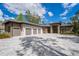 Stunning home featuring a three-car garage and elegant stone accents, set against a backdrop of blue skies and lush greenery at 17038 Medici Way, Bella Collina, FL 34756