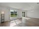 Bright living room with wood floors, big windows with a view of the green yard, and modern light fixture at 1744 Wilson Prairie Cir, Groveland, FL 34736