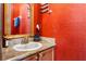 Bathroom with a granite countertop, bronze fixtures, and a framed mirror against red walls at 3653 Calabria Ave, Davenport, FL 33897