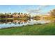 Community pond reflecting the nearby buildings, palm trees, and blue sky at 3704 Via Monte Napoleone Dr, Poinciana, FL 34759