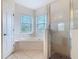 Bright bathroom featuring a soaking tub, a walk-in shower, tile flooring and dual windows for natural lighting at 4560 Daugharty Rd, De Leon Springs, FL 32130