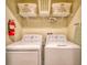 Efficient laundry area showcasing a side-by-side washer and dryer, with storage shelves, and a fire extinguisher at 4967 Windermere Ave, Kissimmee, FL 34746