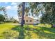 A distant view of a ranch style home with neutral colored paint surrounded by mature trees and a large grass lawn at 866 Gatlin Ave, Orlando, FL 32806