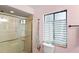 Bathroom with glass door shower and window with striped curtain above toilet at 100 Honeywood Ct, Kissimmee, FL 34743