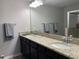 Bathroom featuring double sinks, a granite countertop, dark wood cabinets, and a large mirror at 1013 Flowing Tide Dr, Orlando, FL 32828