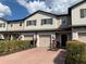 Three-story townhome featuring neutral color scheme, dark shutters, brick driveway and lush landscaping at 1013 Flowing Tide Dr, Orlando, FL 32828