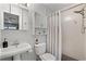 Well-lit bathroom features a pedestal sink, white cabinetry, and tiled shower with curtain at 112 E Cumberland Cir, Longwood, FL 32779