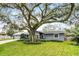 Attractive single-level home with a gray facade, lush front yard, and mature tree providing shade at 112 E Cumberland Cir, Longwood, FL 32779