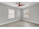 Neutral bedroom featuring light gray walls, a dark ceiling fan, and two windows with blinds at 1129 Ne 12Th St, Ocala, FL 34470