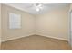 Simple bedroom with neutral carpet and walls, ceiling fan, and window with blinds for a clean and cozy look at 11733 Delwick Dr, Windermere, FL 34786