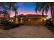 Beautiful home illuminated at dusk with a terracotta roof, lush landscaping, brick paved driveway, and a two car garage at 11733 Delwick Dr, Windermere, FL 34786