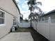 A compact backyard featuring a concrete patio, white fencing, and a large palm tree at 1230 Elegance Ct, Orlando, FL 32828