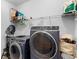 A modern laundry room with front-load washer and dryer, plus overhead shelving at 1714 Leatherback Ln, St Cloud, FL 34771