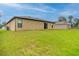 Home's back exterior, showing a well-kept lawn, siding, and view of the sliding glass door at 212 Fig Ct, Poinciana, FL 34759