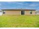 Exterior view of the home's rear showcasing a sliding glass door and a well-maintained lawn at 212 Fig Ct, Poinciana, FL 34759