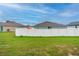 Grassy backyard with a white fence and view of surrounding homes at 212 Fig Ct, Poinciana, FL 34759