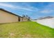 A large backyard with lush green grass and a partial view of the exterior of the home at 212 Fig Ct, Poinciana, FL 34759