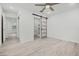 A modern bedroom featuring light wood flooring, a ceiling fan, and a sliding barn door to the ensuite at 230 Hennis Rd, Winter Garden, FL 34787