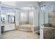 Bright bathroom featuring a soaking tub with tile surround, columns, separate vanities, and a glass shower at 3123 Bentonshire Pl, Longwood, FL 32779