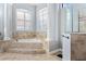 Bright bathroom featuring a soaking tub with tile surround, columns, and a glass shower with tile surround at 3123 Bentonshire Pl, Longwood, FL 32779